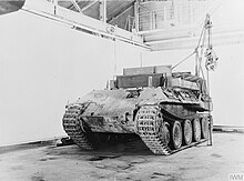 Photographie d’époque d’un Bergepanther vu de trois-quart avant dans un hangar.