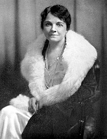 Black and white photo of Martha Kinney Cooper seated and wearing a fur collared coat