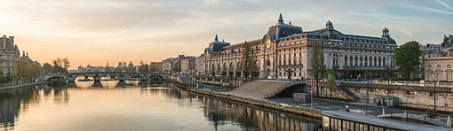 An evening in Paris overlooking the Seine. Old buildings are built up to the shore, and the banks have been replaced with stone walls.