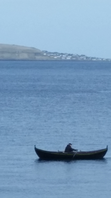 דייג באמצעות סירת משוטים באיי פארו. ברקע המרוחק האי נולסוי