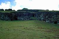 several windowless stone houses with grass roofs