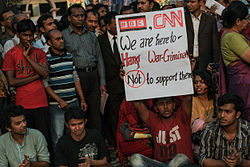 Protester in a crowd holding up English-language poster