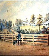 Two persons in front of a fence watching a steam train pass from right to left. A house on a hill is seen in the distance.