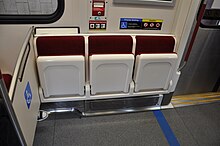 Automatic folding seats in wheelchair accessible position; depending on the individual train, some of these seats use blue velour instead to mark accessibility.