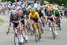 A group of cyclists, with one wearing a yellow jersey