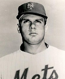 A man in a light baseball jersey with "Mets" across the chest and a dark cap