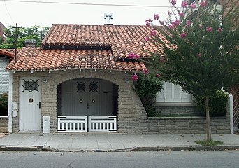 Arch-shaped porch with wooden double gate and a flowerbed at the facade
