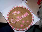 A cookie cake is a large cookie that can be decorated with icing or fondant like a cake. This is made by Mrs. Fields.