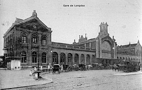 Carrosses et tram devant la gare, après la pose de la fontaine, visible à gauche.