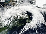 A satellite image of a large non-tropical cyclone over Eastern Canada with cyclonically organized clouds with a north to south oriented line of clouds well east of the storm