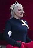 White woman with blonde hair wearing a black outfit and smiling
