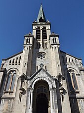 Photographie en contre-plongée du portail et du clocher d'une église.