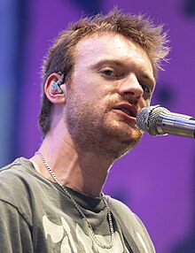 O'Connell glancing towards a camera while singing into a microphone