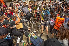 A large group of protestors converging on the statue in the moments after it was pulled down, stamping on it and dismantling parts of it