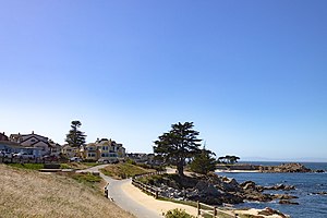Reproduction of the same historical photograph 50 years later, June 2022, taken from the same physical location, showing the Monterey Bay Coastal Trail where the old railroad bed is.