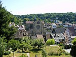 Blick über einen Berghang auf die Abteikirche Otterberg