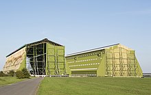 A picture of two green airship sheds taken on a clear day