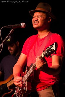 Son Little with his eyes closed and playing a guitar