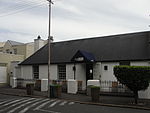 Single storey cottage attached to no. 2.6-a; full hipped corrugated iron roof; sash windows (24 panes); stable door with small-paned glazing; most of joinery is possibly original; low boundary wall of plastered brick piers and cast iron railings; Type of site: Commercial Previous use: Residential. Current use: Shop/Gallery/Tea room.