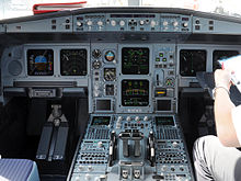 Cockpit of the A330. All instruments and displays are switched on. Two seats occupy both sides of the cockpit, separated by a centre console.