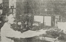 A grainy, sepia-toned image showing a man at a receiving station, a desk with various pieces of equipment