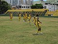 Jogadores em treino no estádio com as arquibancadas ao fundo.