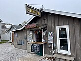 A building with an open window looking in with a menu next to it and a sign that reads “Cheese” above it.