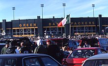 Lambeau Field with parked cars and people in the foreground