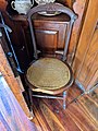 Chair in living room, with beaver gnaw marks on the front of the seat.