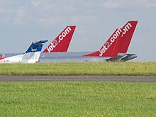 plusieurs dérives d'avion de ligne, visibles par-dessus un monticule. Chacune porte le nom d'une compagnie aérienne.