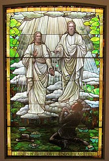 a stained glass window featuring two illuminated beings dressed in white appearing to a young boy