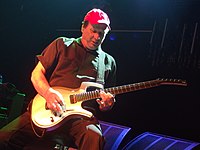 A man in a red hat playing a yellow guitar