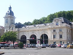 Vue d’un bâtiment blanc à trois arches, orné d’une tour.