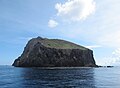 Redonda viewed from the southeast, with waves breaking on a rock cobble beach