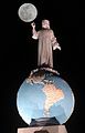The Jesus Christ statue on top of the globe sphere of planet Earth on a full moon night.