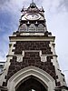 View up a clock tower with a stone base and iron railings