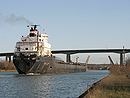 Bateau passant le canal Welland, avec les ponts Homer Lift Bridge et Garden City Skyway en arrière plan.