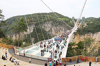 Groups of people crossing the Zhangjiajie Grand Canyon Glass Bridge in China. Picture taken from the west side of the gorge.