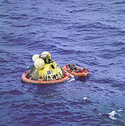 Photographie en couleur de la capsule d'Apollo 11 flottant en mer lors de la récupération des astronautes.