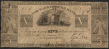 Five dollar bill. The illustration includes female figure with a rake and grain; and a seated Justice with sword and scales. The inscription reads Inscription: "THE HARRISBURG BANK Promises to pay FIVE dollars on demand to or bearer."