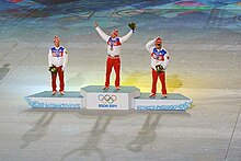 Vue de loin du podium des 50 kilomètres des Jeux de Sotchi, le vainqueur levant les bras en l'air.