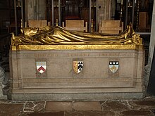 A stone rectangular monument, with the golden figure of a man dressed in robes and wearing a mitre lying on top, with his hands together in a gesture of prayer. The words "Edward Stuart Talbot" on the side in gold, with three shields bearing coats of arms below. At the bottom, in gold: beneath the first shield, "1870 Keble 1888"; beneath the second, "1834–1944"; beneath the third, "1889 Leeds 1895"