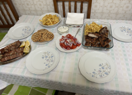 A traditional table with Greek food ordered from a taverna/ souvlatzidiko