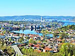 Foto einer Stadt, die an einem Fluss liegt. Im Vordergrund Wohnhäuser, weiter entfernt liegt industrielle Bebauung.