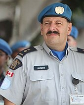 a person in a police uniform wearing a United Nations blue beret