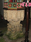 the 15th-century octagonal font with bowl panels decorated with tracery with the underside of the bowl supported by carved demi-figures of angels. The pedestal has four hunched lions, one to each corner with a double tracery panel between each lion.