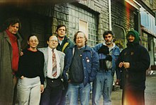 A group of seven people stand near the entrance of a building.