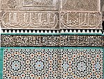 Zellij tilework featuring geometric motifs (below), with sgraffito-type tiles (middle) and stucco decoration (above) featuring Arabic calligraphy