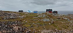 Part of the village of Cape Tobin with an iceberg in the background