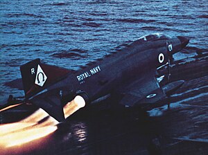 A jet aeroplane with afterburners lit just before launch from an aircraft carrier